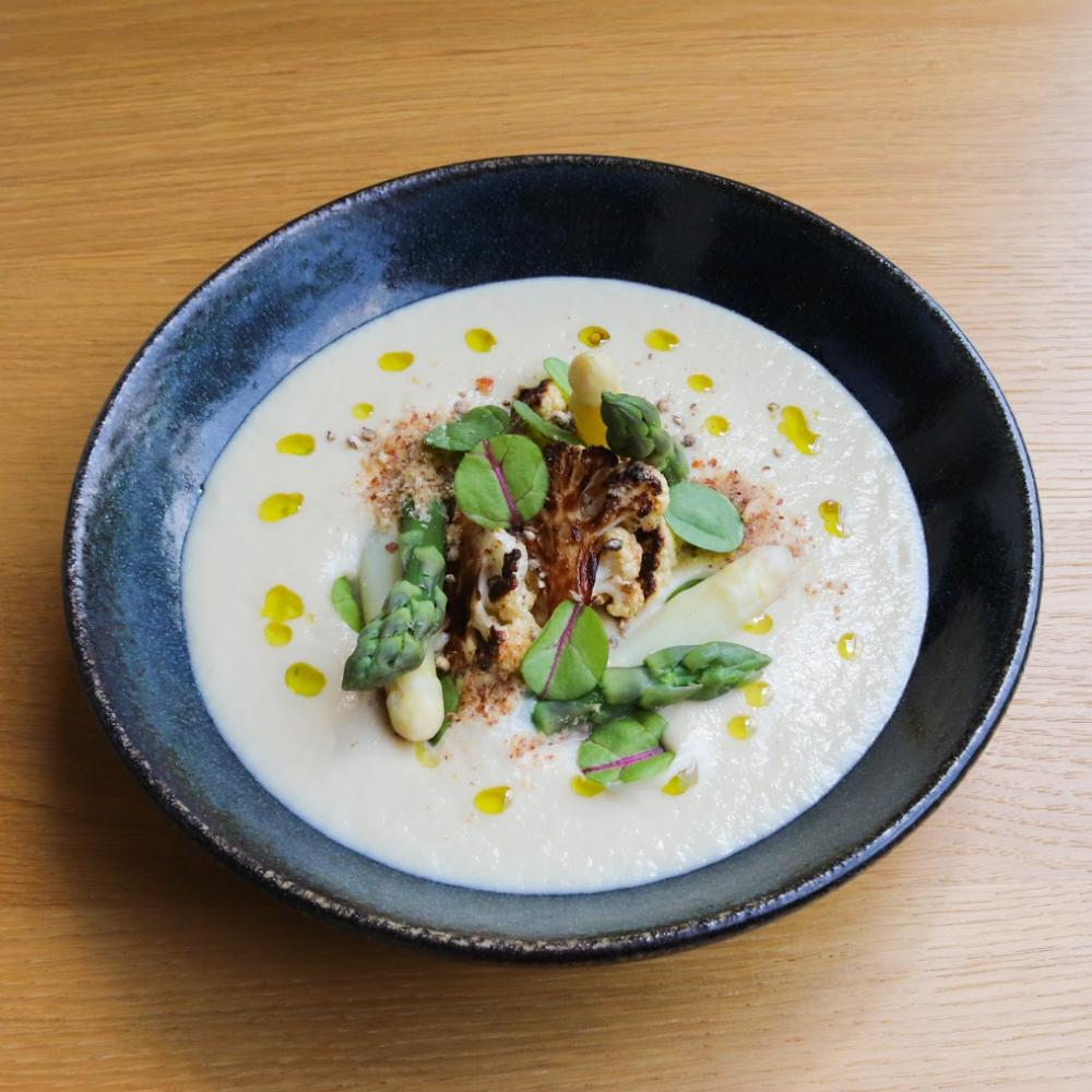 Krém z pečeného květáku s bílým Kampotský pepř, karamelizovaným květákem, blanšírovaným chřestem a uzenými mandlemi